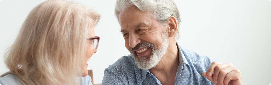 an older man and woman smiling at each other