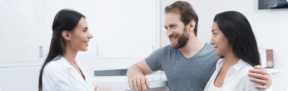 a man with his arm around a woman as they speak to their dentist