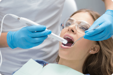 woman in a dental chair with her mouth open with dental tools inside