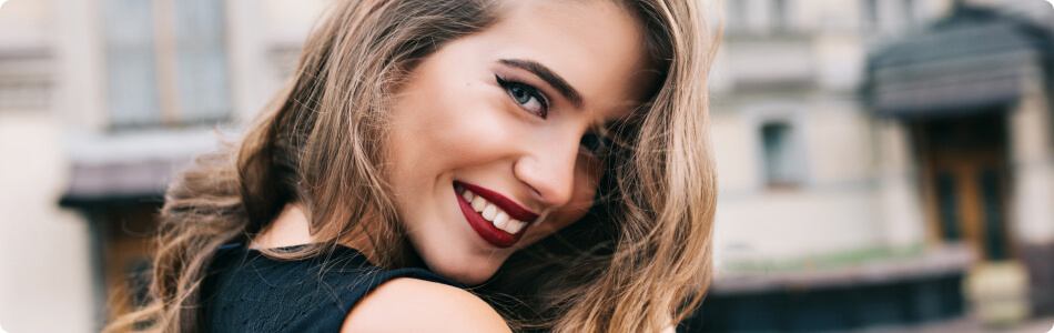 beautiful young woman with red lipstick smiling with her head slightly tilted down