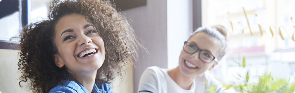 two woman sitting together and laughing