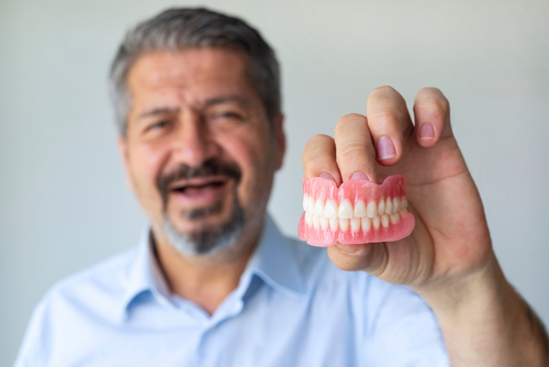man holding set of dentures